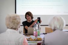 Der Mobilreferent sitzt mit Besucherinnen an einem Tisch und erkl&auml;rt etwas am Handy.