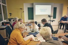 Eine Gruppe von Senioren sitzt am Tisch und macht sich Notizen