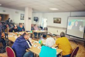 Senioren sitzen am Tisch und hören dem Vortrag des Digitalen Engels zu