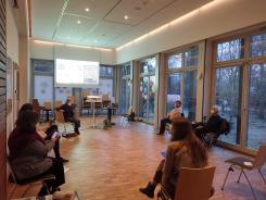 Teilnehmende der Veranstaltung sitzen im Raum und schauen auf ihre Smartphones