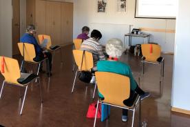 Senioren und Seniorinnen sitzen im Raum und schauen auf Leinwand