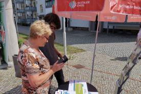 Eine Dame steht an unserem Stand und zeigt unserem Referenten Johannes Diller etwas auf ihrem Smartphone