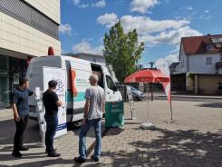 drei Herren stehen vor dem Infomobil und unterhalten sich