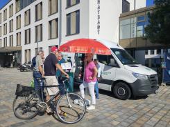 Besucher:innen stehen vor dem Infomobil und unterhalten sich 