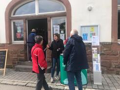 Theresa informiert eine Besucherin und einen Besucher am Infostand vor dem Begegnungszentrum über sichere Passwörter.