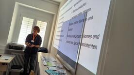 Referent Johannes steht vor einer auf die Wand projizierten Präsentation 