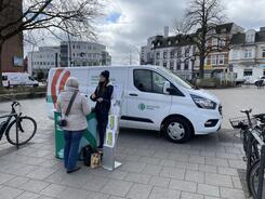 Petra steht mit einer Seniorin am Info-Stand vor dem Info-Mobil und ist mit ihr im Gespräch. Am linken und rechten Bildrand steht jeweils ein Fahrrad.