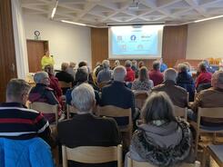 DIe über 30 Teilnehmenden sitzen und schauen auf die Endfolie der Präsentation, die auf einer Leinwand gezeigt wird.