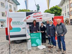 Johannes steht neben mehreren Personen vor dem Infomobil.