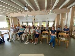 In einem Gemeindehaus sitzen in zwei Stuhlreihen knapp 20 Frauen und blicken nach vorne in die Kamera.