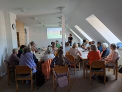 Die Teilnehmenden sitzen im Raum und blicken nach Vorne zu Referent Johannes.