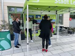 Theresa und drei Seniorinnen stehen unter einem Pavillon der Stadt Leuna. Links neben Theresa ist unser Messetresen.