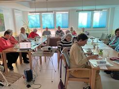 Die Teilnehmerinnen sitzen an Tischen in U-Form und einige f&uuml;llen Feedbackb&ouml;gen aus.