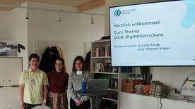 Theresa, sowie Aniane Emde vom Polizeipr&auml;sidium und unsere Kooperations stehen links neben der Leinwand mit Willkommensfolie und l&auml;cheln in die Kamera.