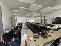 Im Weitwinkelmodus sind knapp 30 Senior:innen an zwei langen Tischen abgebildet. Die einzelnen Personen kann man nicht erkennen.