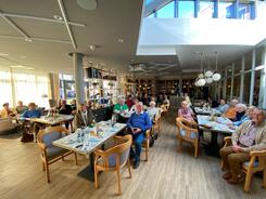 Im Weitwinkelmodus sind knapp 30 Senior:innen an mehreren Tischen abgebildet. Die einzelnen Personen kann man nicht erkennen.