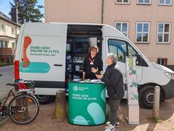 Eine Dame steht vor dem Infomobil und blickt zum Referenten Johannes 