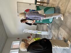 Mobilreferentin Theresa steht mit &auml;lteren Frauen am Infostand in der Stadthalle und l&auml;chelt.