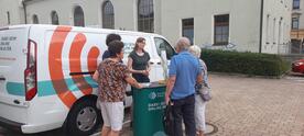 Petra steht mit vier Senior:innen am Info-Stand vor dem Info-Mobil.