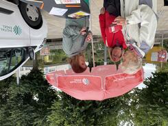 Theresa ber&auml;t zwei Seniorinnen vor dem Sonnenschirm links neben dem Infomobil.