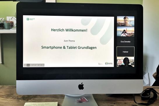 Computer Monitor mit dem Bild einer Videokonferenz in der eine Präsentation zum Thema Smartphone & Tablet Grundlagen zu sehen ist
