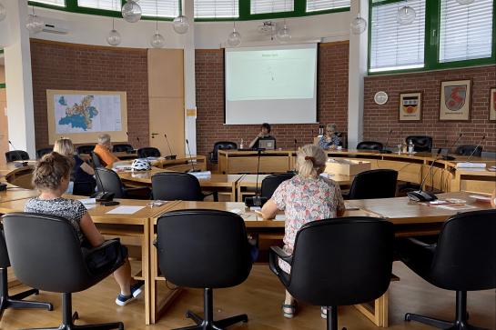 Senioren sitzen im Raum und schauen auf Leinwand