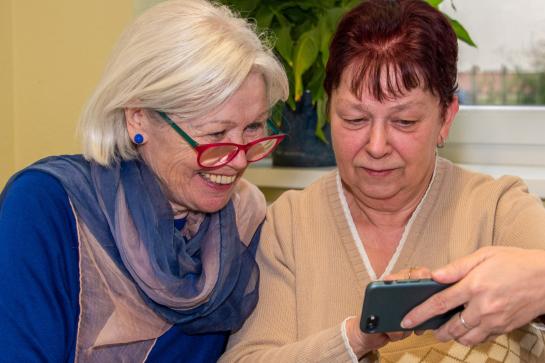zwei Seniorinnen schauen sich ein Smartphone an