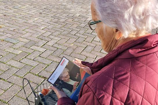Seniorin steht auf dem Marktplatz in Ratzeburg und blättert im Buch