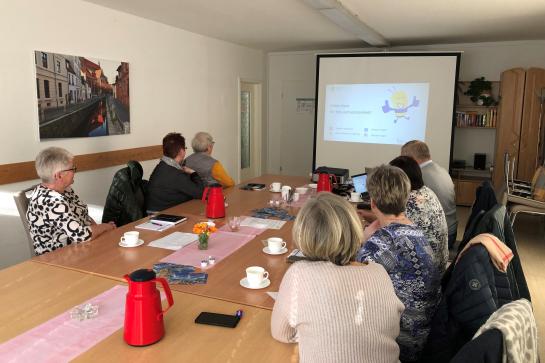 Senioren in Wismar sitzen im Raum und schauen auf Leinwand