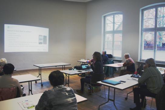 Die Teilnehmenden sitzen im Raum und schauen zur Präsentation an der Wand