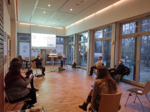 Teilnehmende der Veranstaltung sitzen im Raum und schauen auf ihre Smartphones