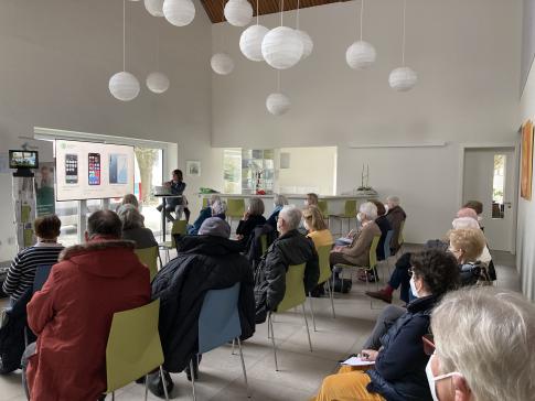 Die Teilnehmenden sitzen im Raum und schauen zur Präsentation nach vorne auf einen großen Flachbildschirm