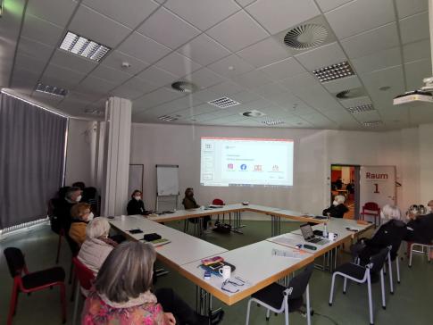 Die Teilnehmenden sitzen im Raum und schauen zur Präsentation an der Wand