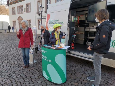 Besucherinnen stehen vor dem Infomobil und unterhalten sich mit unserem Referenten