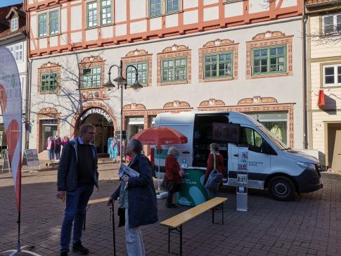 Interessierte Menschen stehen vor dem Infomobil und unterhalten sich miteinander