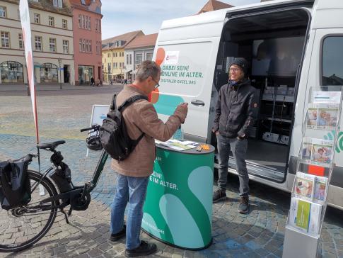 ein Besucher steht mit seinem Fahrrad vor dem Infomobil und unterhält sich mit unserem Mobilreferenten.