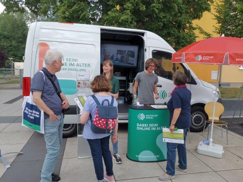 Besucherinnen stehen vor dem Infomobil und unterhalten sich mit unseren Referent:innen Petra Rollfing und Johannes Diller