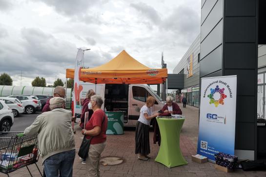 Besucher:innen stehen vor dem Infomobil und unterhalten sich 