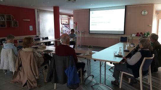 Die Teilnehmenden sitzen im Raum und schauen zur Präsentation an der Wand