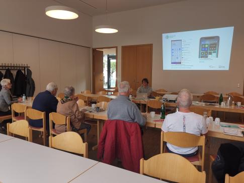 Die Teilnehmenden sitzen im Raum und schauen zur Präsentation an der Wand