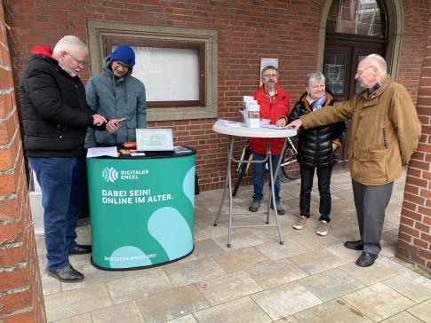 Unser Referent Johannes steht am Infostand und zeigt einem Herrn etwas am Smartphone