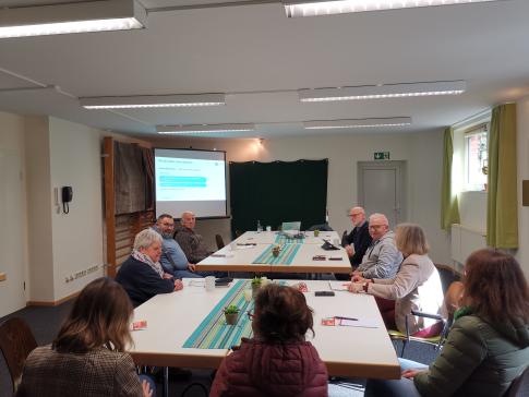 Die Teilnehmenden sitzen im Raum und schauen zur Präsentation an der Wand