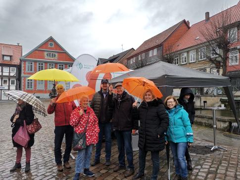 Gruppenbild von Besucher:innen, die Regenschirme halten