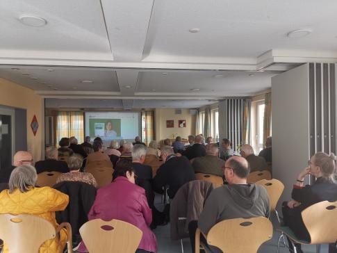 Die Teilnehmenden sitzen im Raum und schauen zur Präsentation an der Leinwand