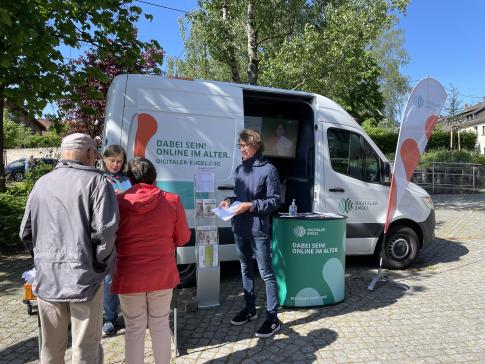 Besucherinnen stehen vor dem Infomobil und unterhalten sich mit unserem Referenten Johannes