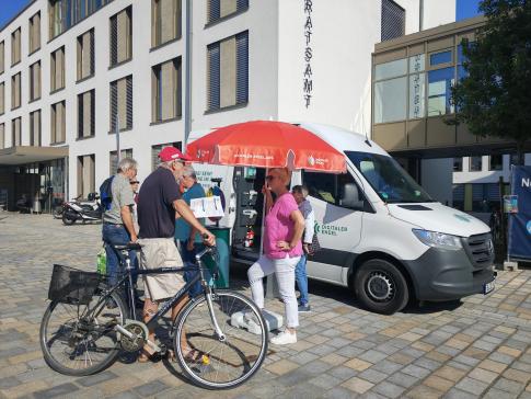 Besucher:innen stehen vor dem Infomobil und unterhalten sich 