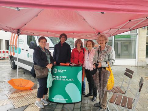 Einige Besucherinnen stehen neben unserem Referenten Johannes unter einem Pavillon vor dem Infomobil