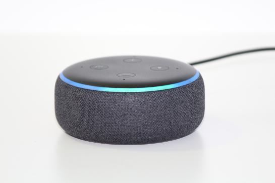 Ein runder Lautsprecher mit Alexa ist in einem weißen Raum mittig platziert
