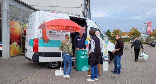 Besucher:innen stehen vor dem Infomobil und unterhalten sich mit unserem Referenten