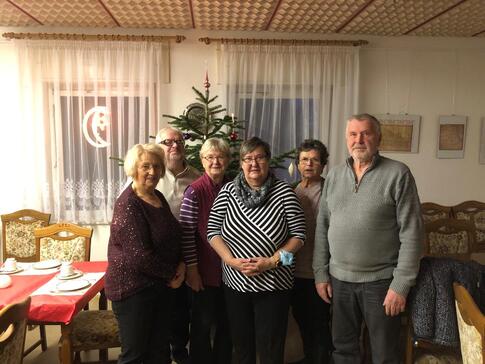 Vier Teilnehmerinnen und zwei Teilnehmer stehen vor einem Tannenbaum im Ortwiger Gemeindezentrum und lächeln in die Kamera.